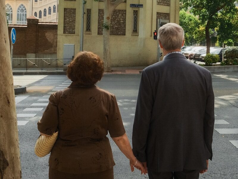a man and a woman walking down a street holding hands
