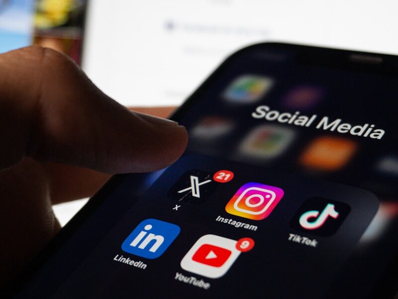 A person holding a smart phone with social media on the screen