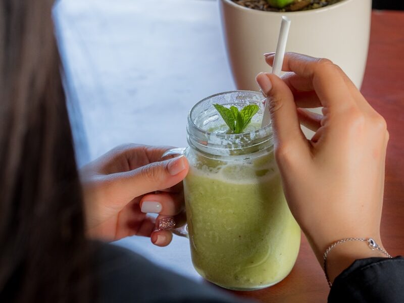 person holding clear drinking glass with green liquid