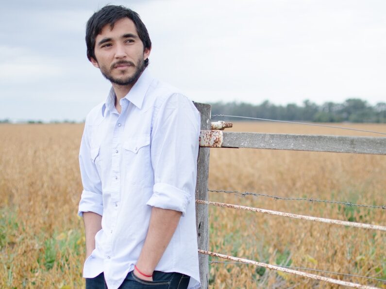 a man leaning against a fence in a field