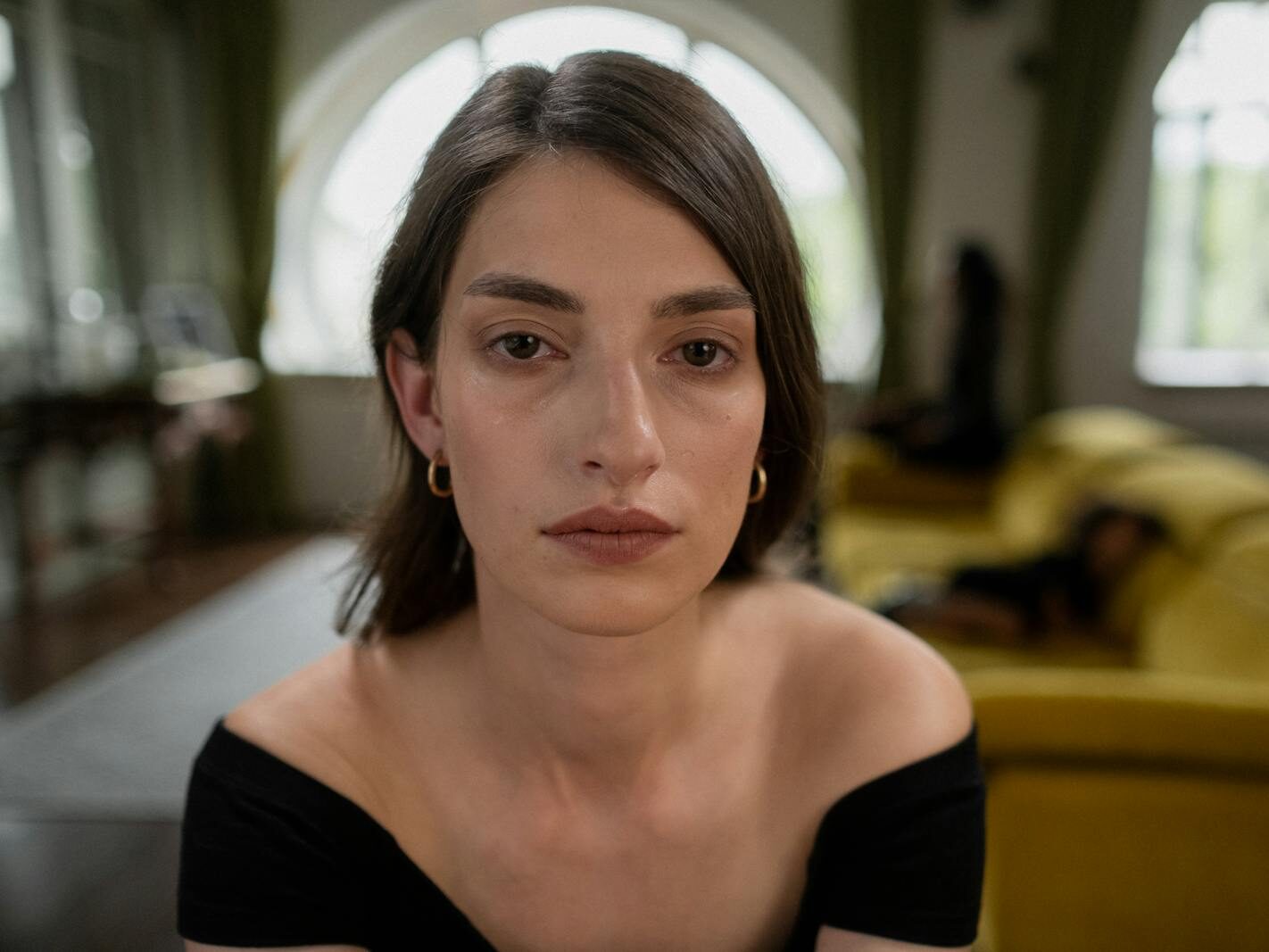 A close-up portrait of a woman with a calm expression, indoors, with thoughtful ambiance.