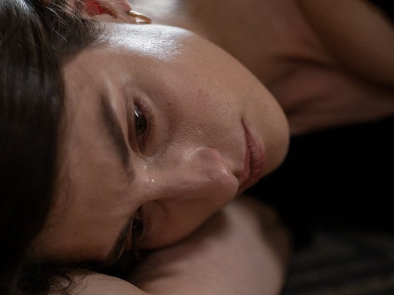 Close-up of a woman lying down, expressing sadness and crying.