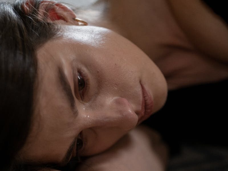 Close-up of a woman lying down, expressing sadness and crying.