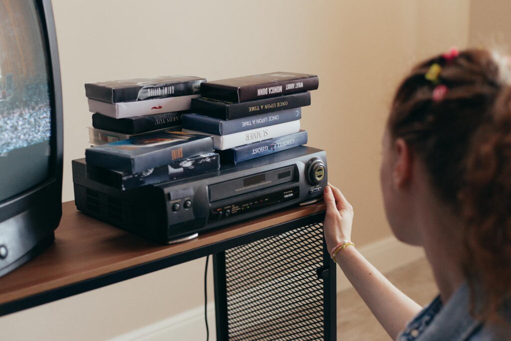 Young woman engaging with retro VHS tapes and a classic VCR setup.