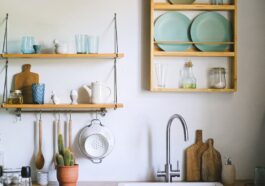 Cozy kitchen featuring rustic open shelving, green plants, and elegant dishware.