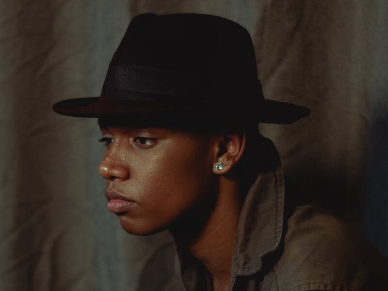 Elegant portrait of a man wearing a fedora, showcasing contemplative fashion style.