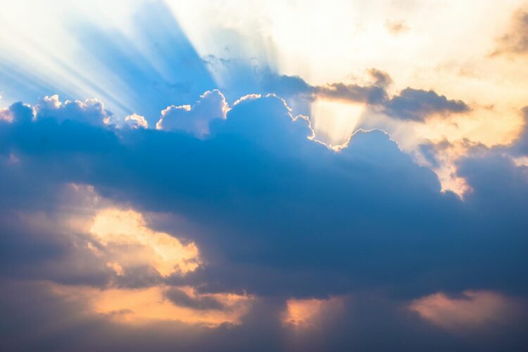 A dramatic sky with sunbeams piercing through clouds during a vibrant sunset.