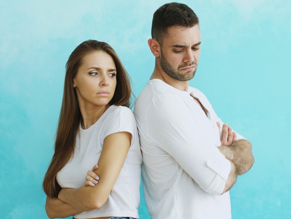 Couple standing back to back with arms crossed