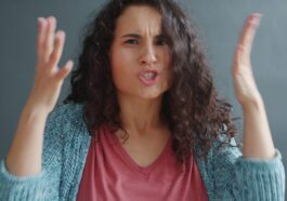 Woman with curly hair looking angry and frustrated.