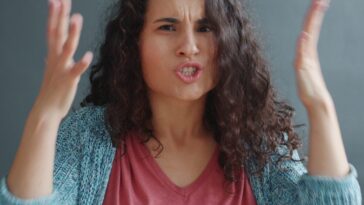 Woman with curly hair looking angry and frustrated.