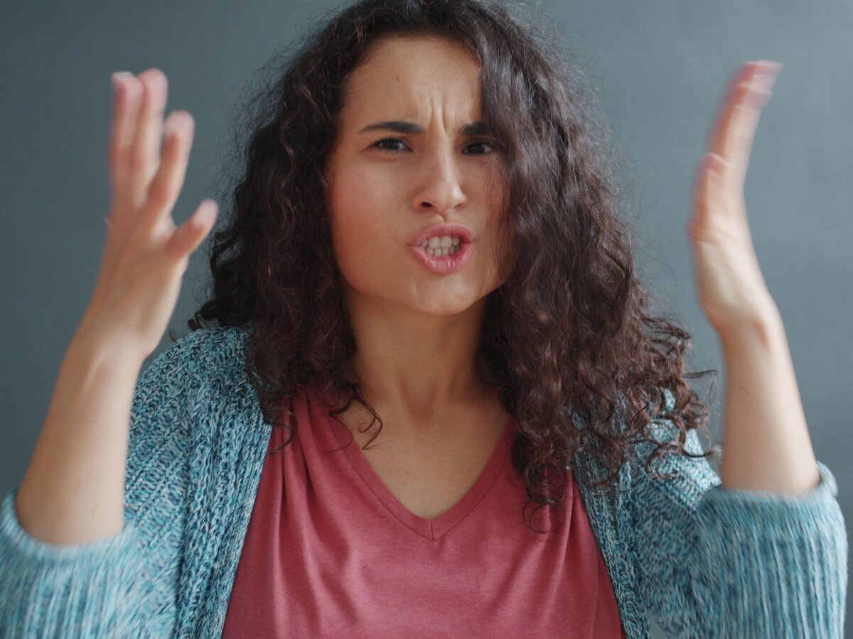 Woman with curly hair looking angry and frustrated.