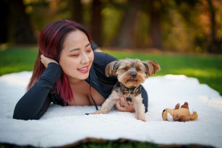 Woman and Yorkshire Terrier enjoying a sunny day on a blanket in Los Altos park.