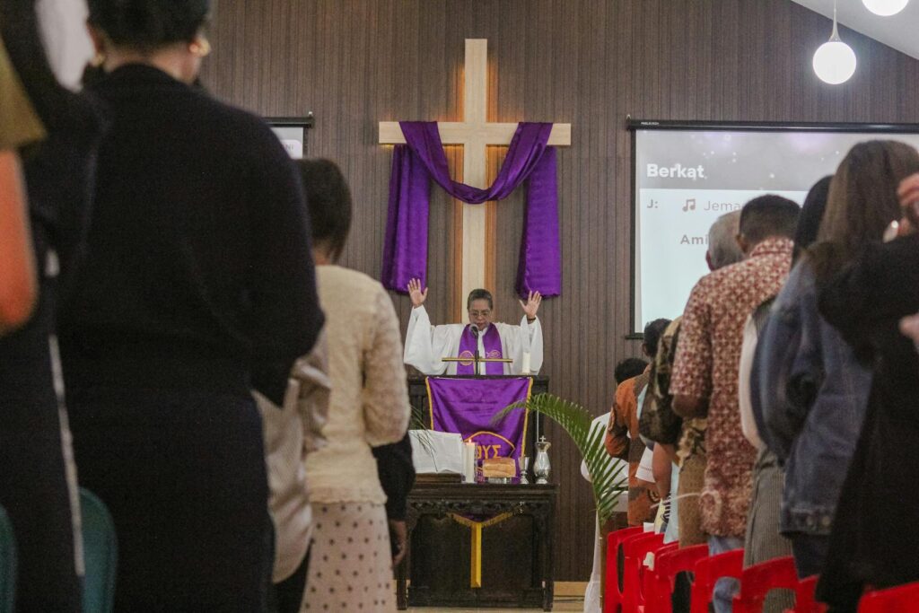Congregational gathering for a church service in Bali as the priest leads the worship.