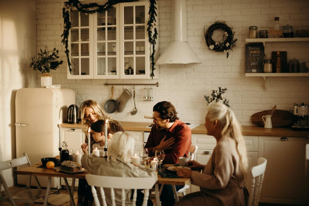 Family enjoying a holiday meal in a cozy, warmly lit dining room setting with candles and festive decor.