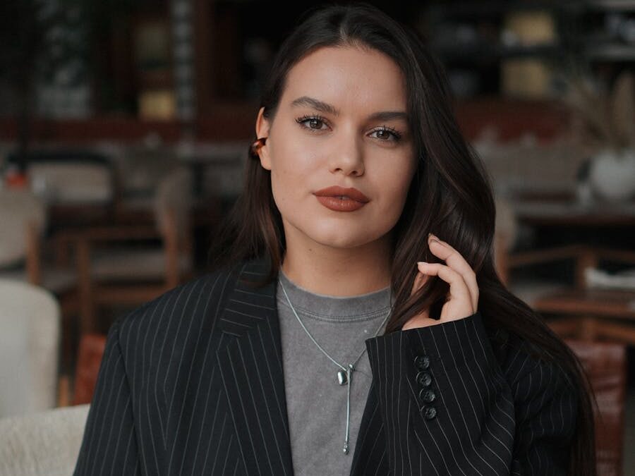 Elegant woman indoors with striking makeup and fashion style, exuding confidence.