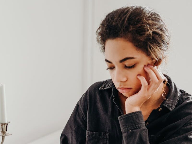 Pensive woman reading a book and enjoying coffee indoors, captured in a contemplative moment.