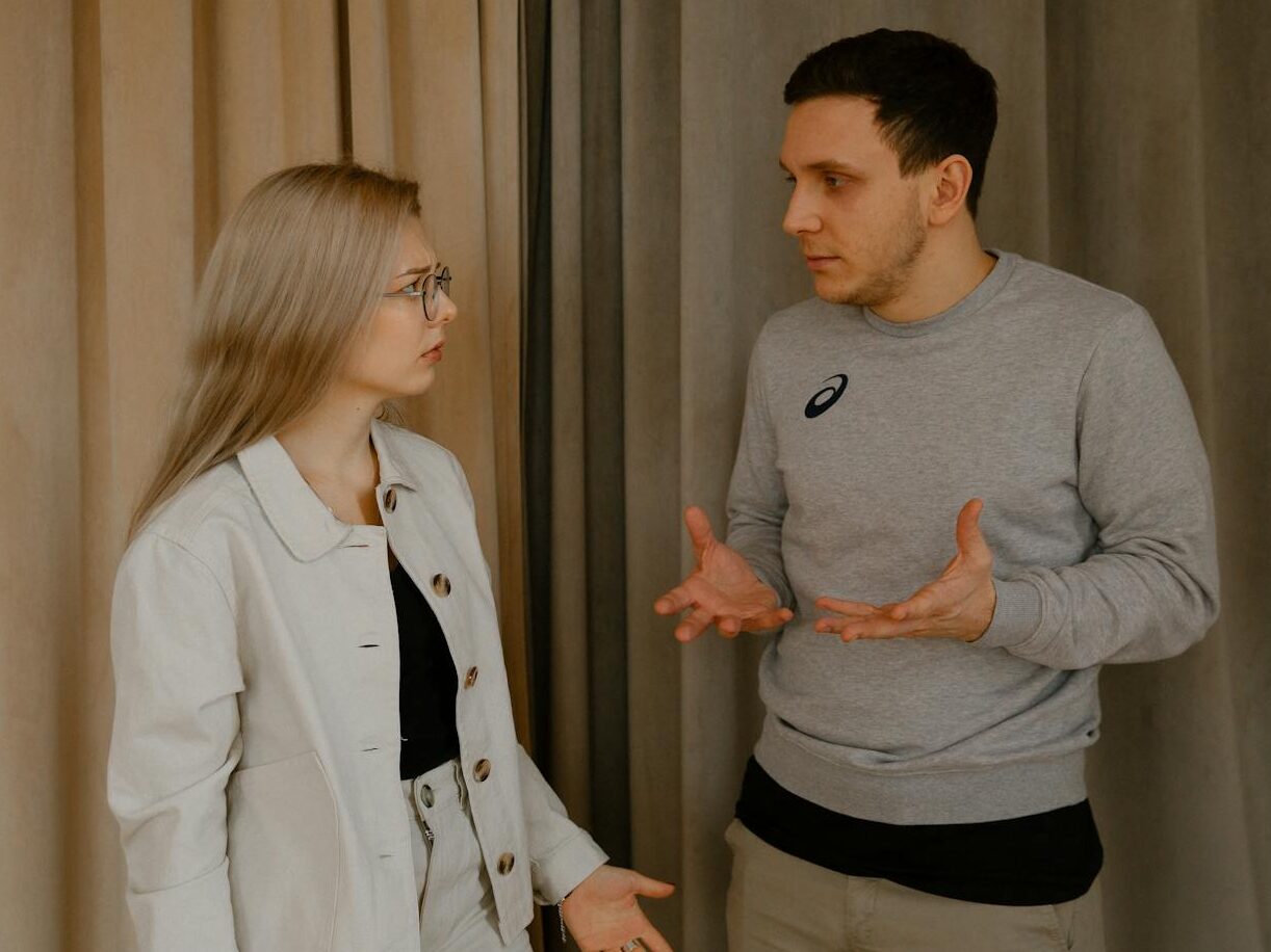 A young couple passionately discussing indoors, capturing intense emotions and gestures.