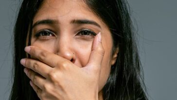 Emotional portrait of a woman covering her mouth in shock. Studio shot.
