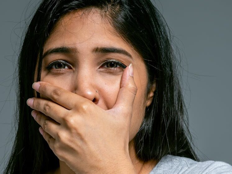 Emotional portrait of a woman covering her mouth in shock. Studio shot.