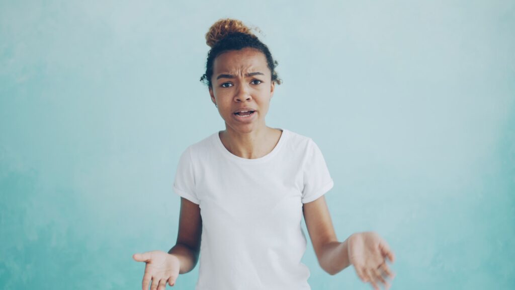 Young woman with confused expression against blue background