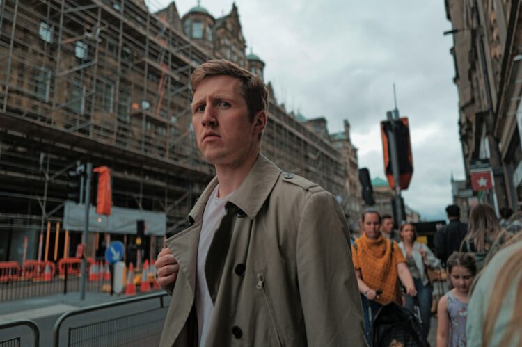 A man in a trench coat walking down the street