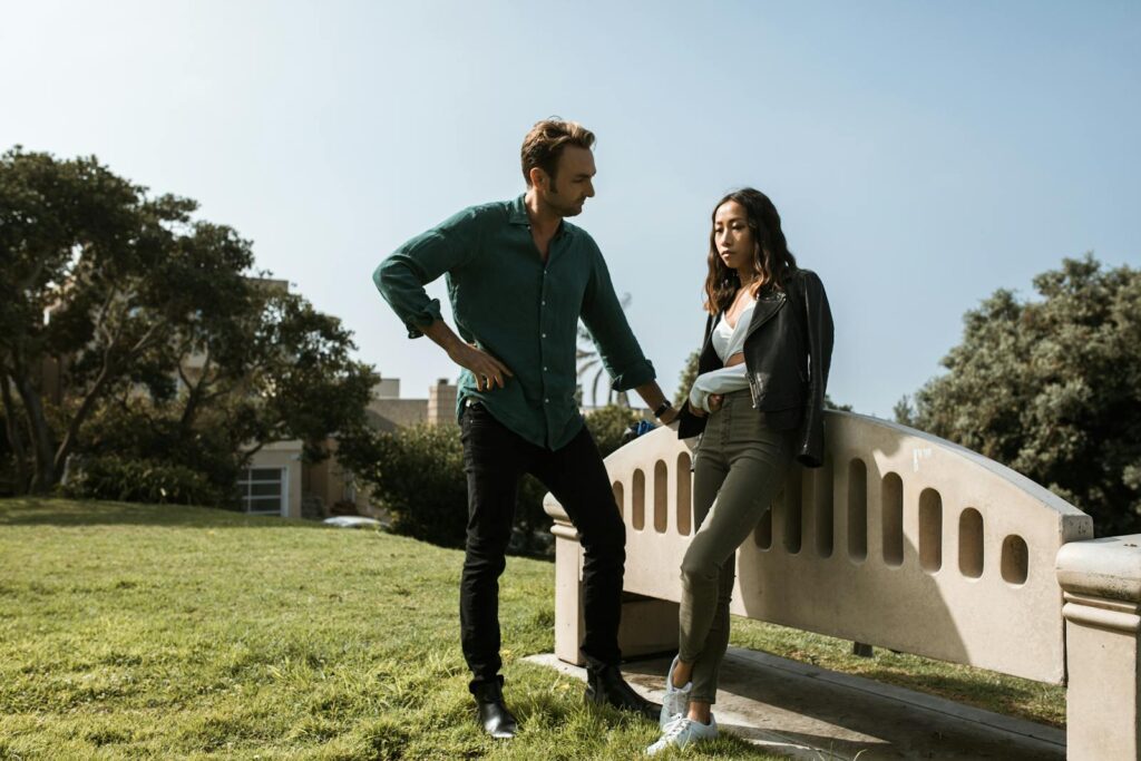 A couple in a tense discussion in a park setting, conveying relationship conflict.