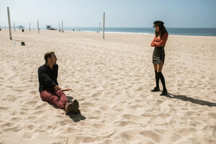 A couple discussing intensely on a sunny beach. Relationship dynamics captured vividly.