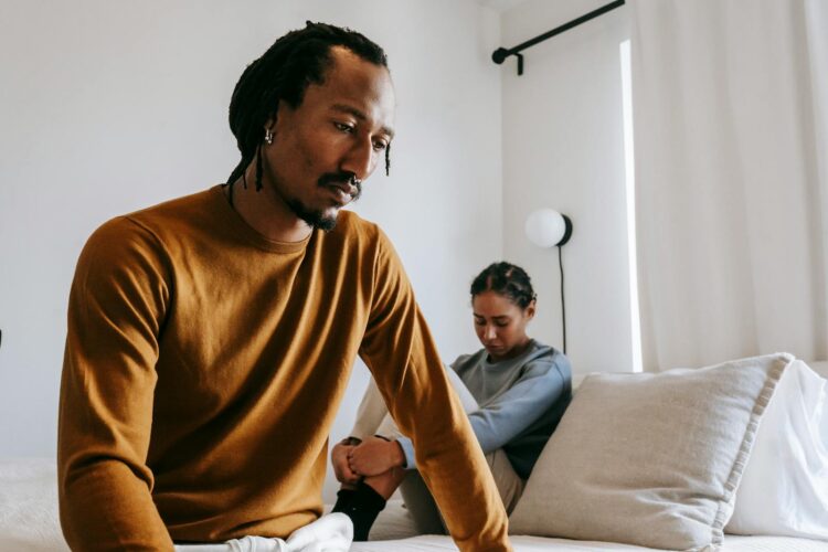 A thoughtful couple facing relationship issues in a bedroom setting.