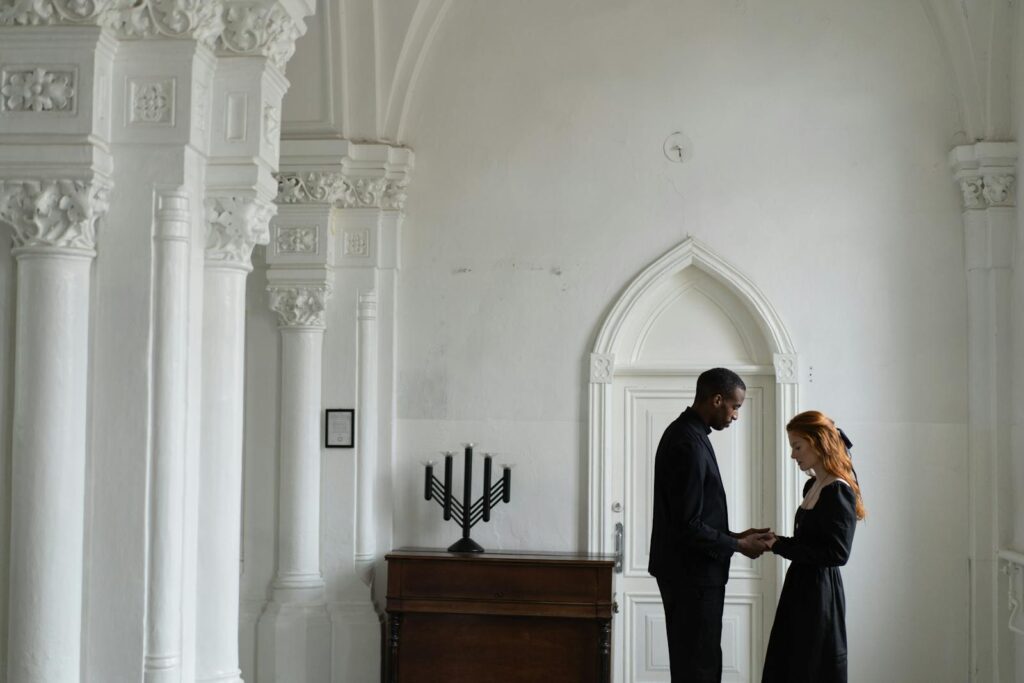 A solemn moment inside a chapel with an interracial couple praying, highlighting themes of unity and compassion.