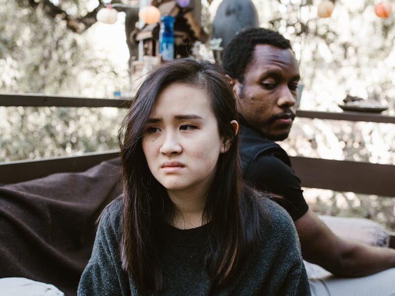 A couple sitting outdoors, showing signs of disagreement and emotional conflict.