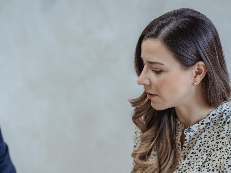 Crop focused female with long wavy hair talking about business at table with microphone in office