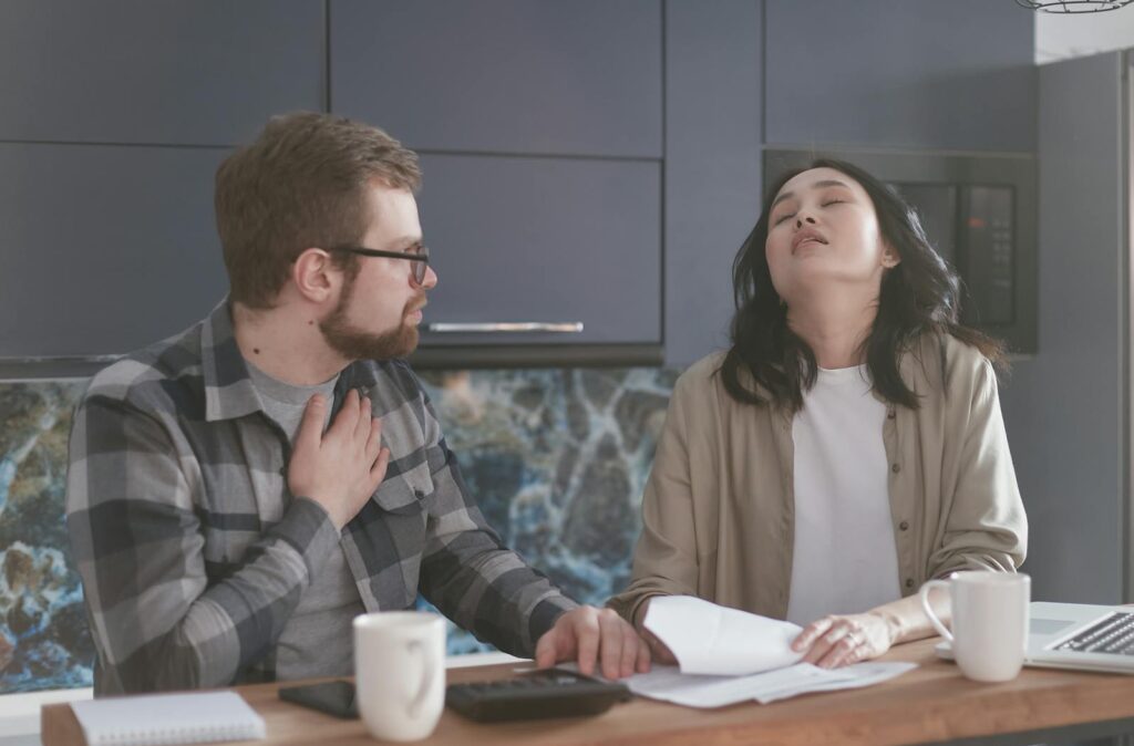 A couple experiencing stress while discussing finances in a modern kitchen setting.