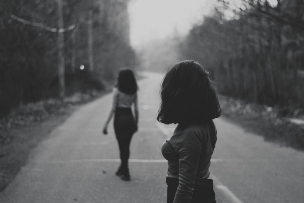 woman in black jacket walking on road during daytime