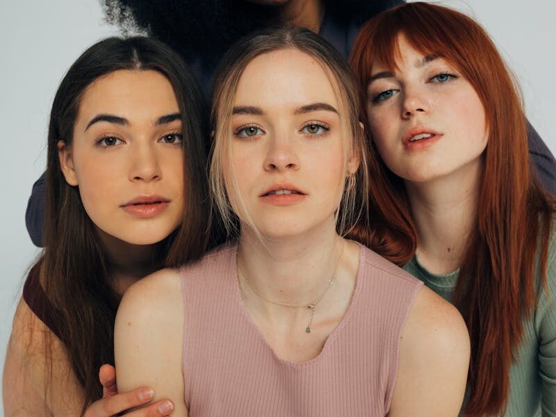 A diverse group of women posing elegantly in a studio setting.