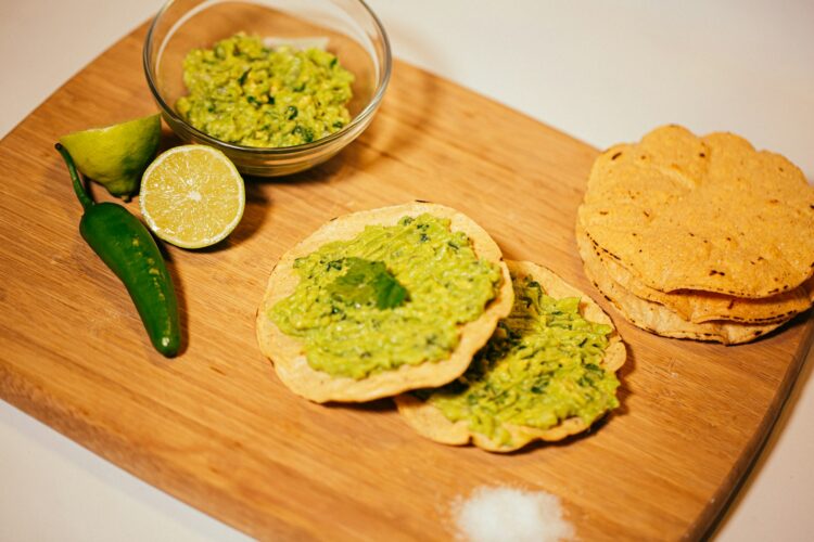 a wooden cutting board topped with crackers and guacamole
