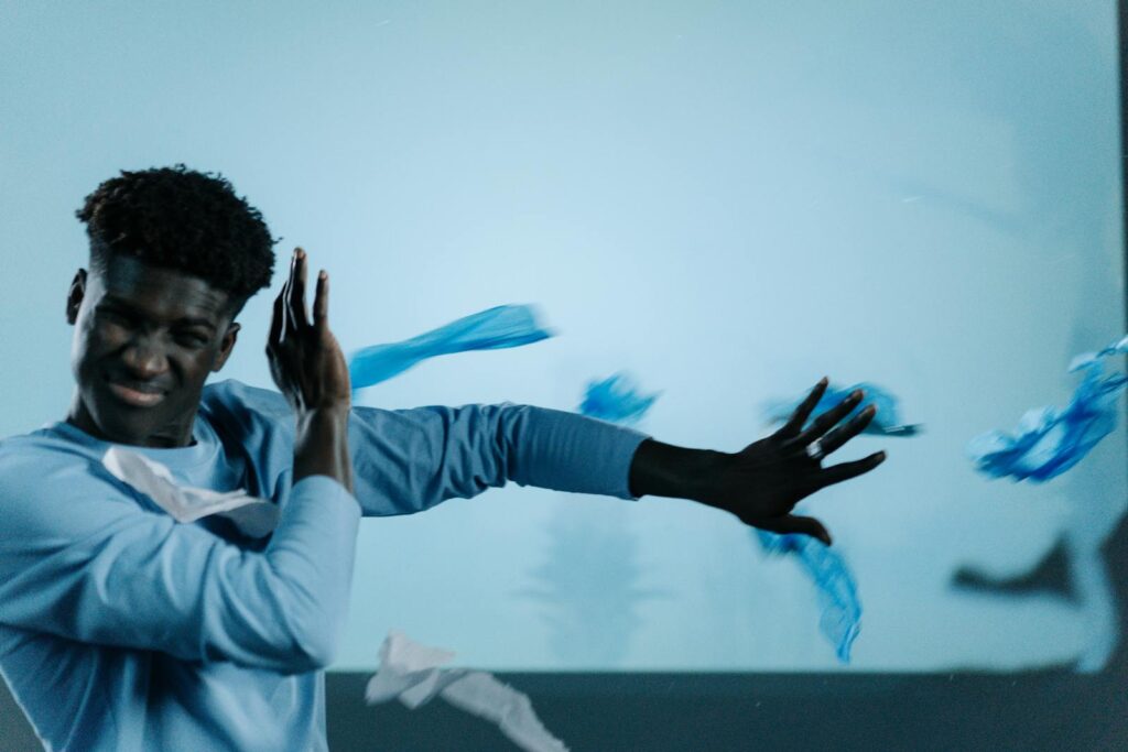 A man shields himself from flying plastic waste indoors.