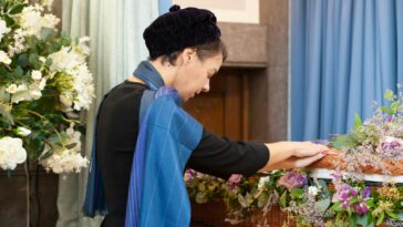 a woman arranging flowers in a wicker basket