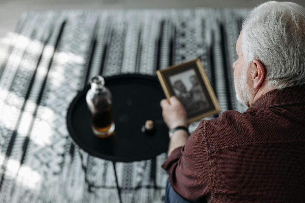 Senior man holding a picture frame, evoking nostalgia and reflection indoors.