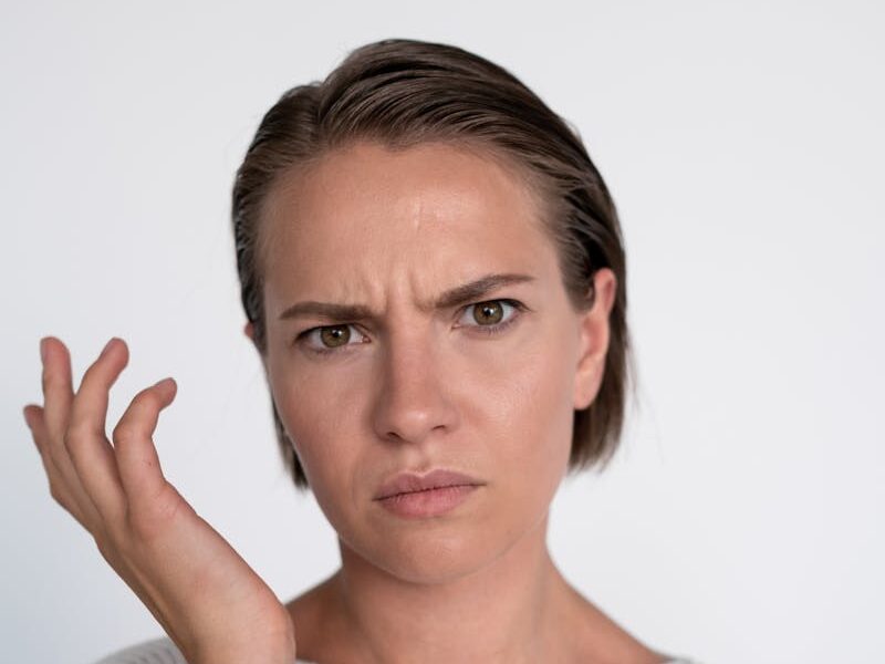 A confused young woman with a questioning facial expression on a white background.