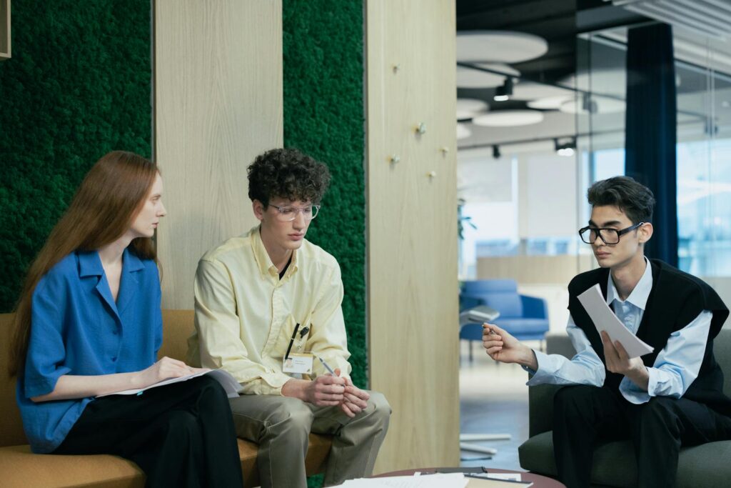 A diverse group of young professionals discussing work in a modern office setting.