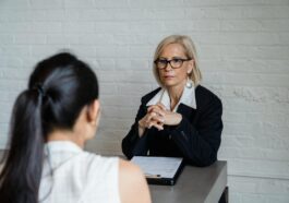 Professional businesswoman in a black blazer conducting an interview indoors.
