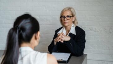 Professional businesswoman in a black blazer conducting an interview indoors.