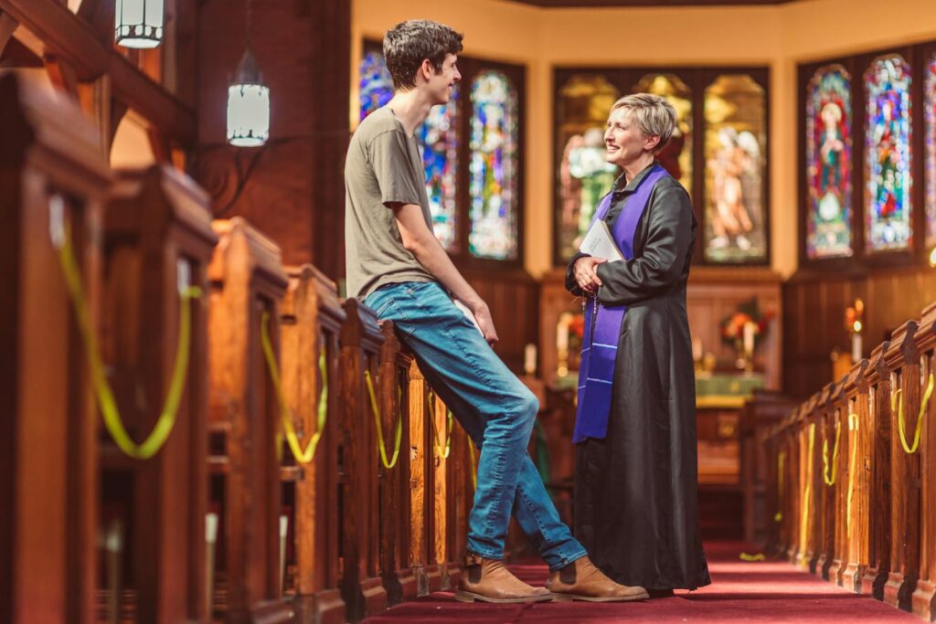 A pastor and parishioner having a friendly conversation inside a church.