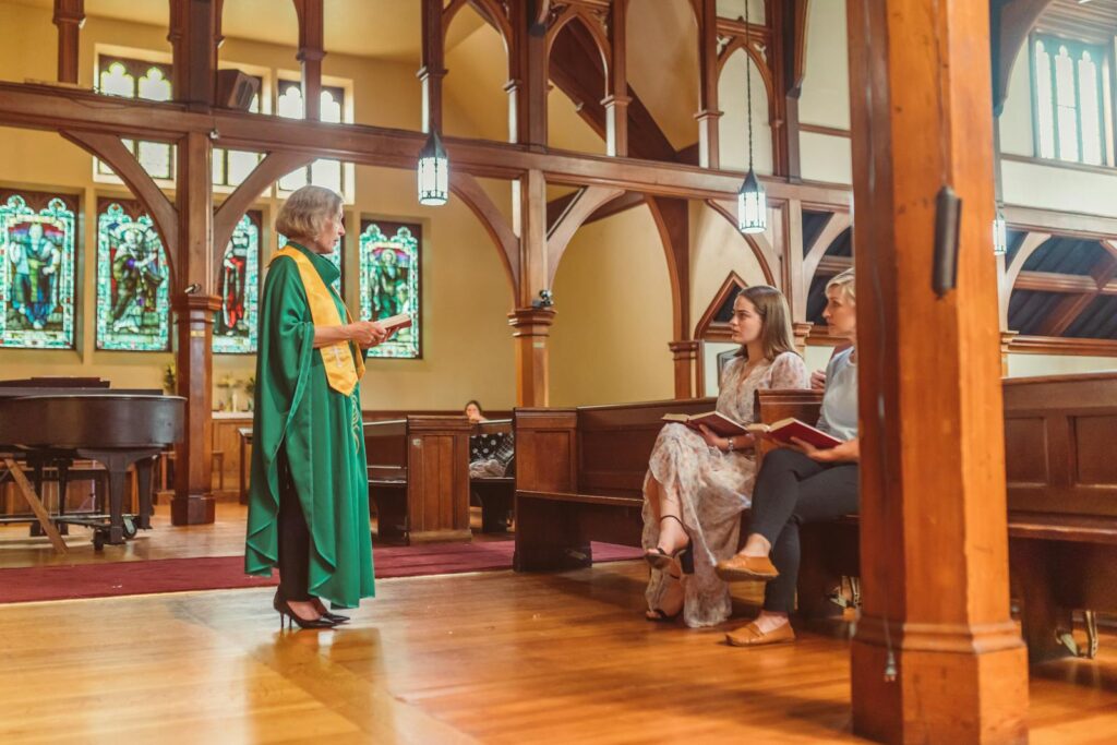 A church service with a preacher addressing seated congregants inside a traditional setting.