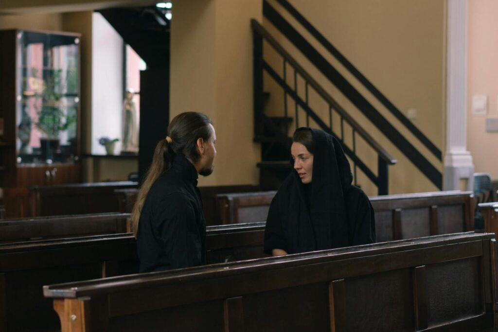 A thoughtful dialogue between a man and a woman in a quiet church setting.