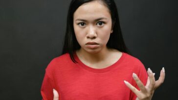 A young woman with expressive hands showing emotions against a dark background.