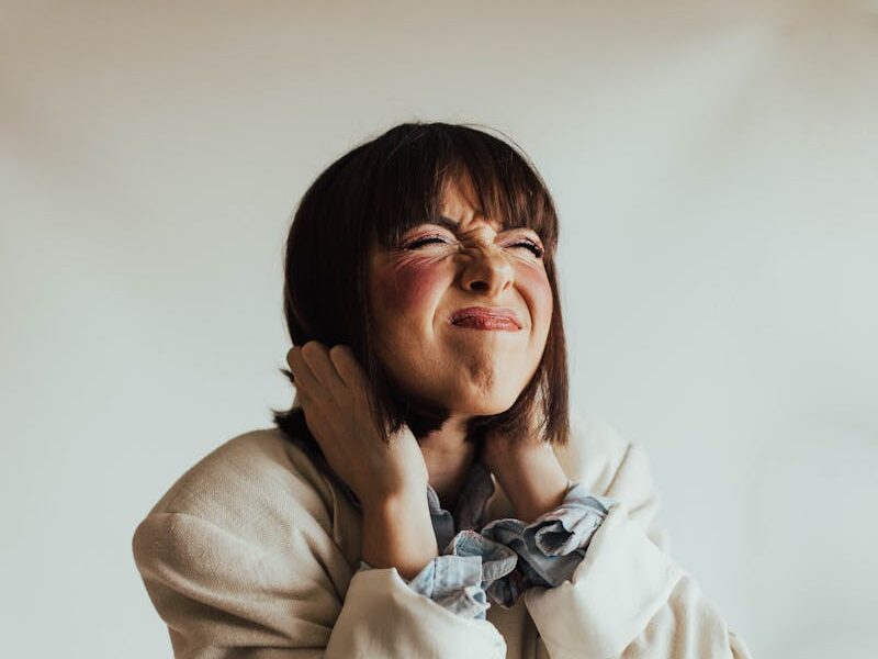 Woman in beige suit expressing frustration in a studio shot.