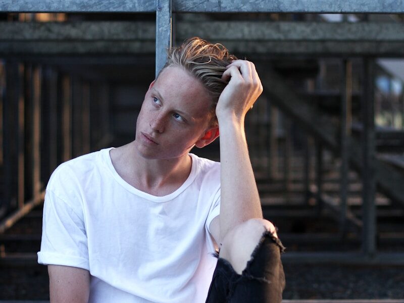 man sitting on floor wearing white crew-neck T-shirt