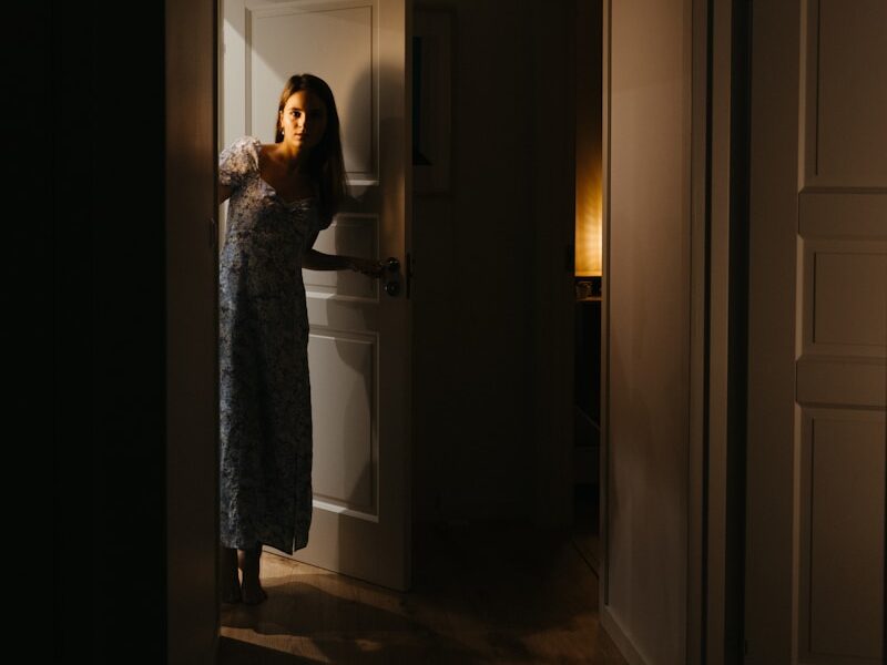 a woman is standing in a dark hallway
