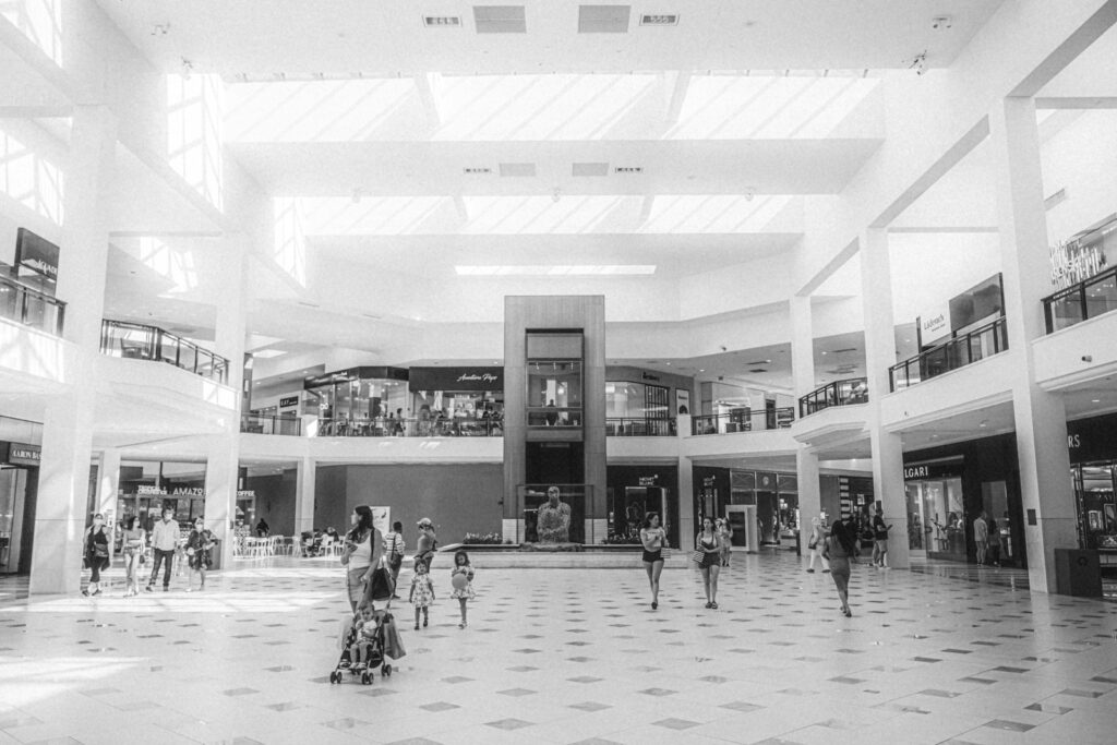 a black and white photo of people in a shopping mall